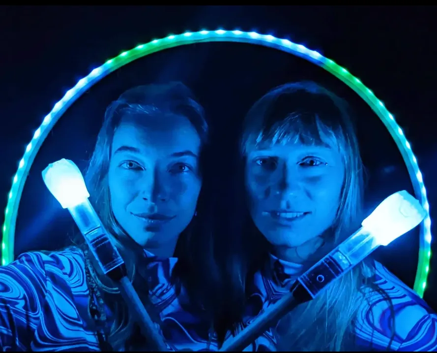 Two performers framed by a glowing LED hoop