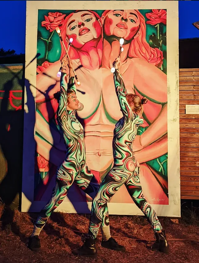 Duo performing with LED props in front of a large mural