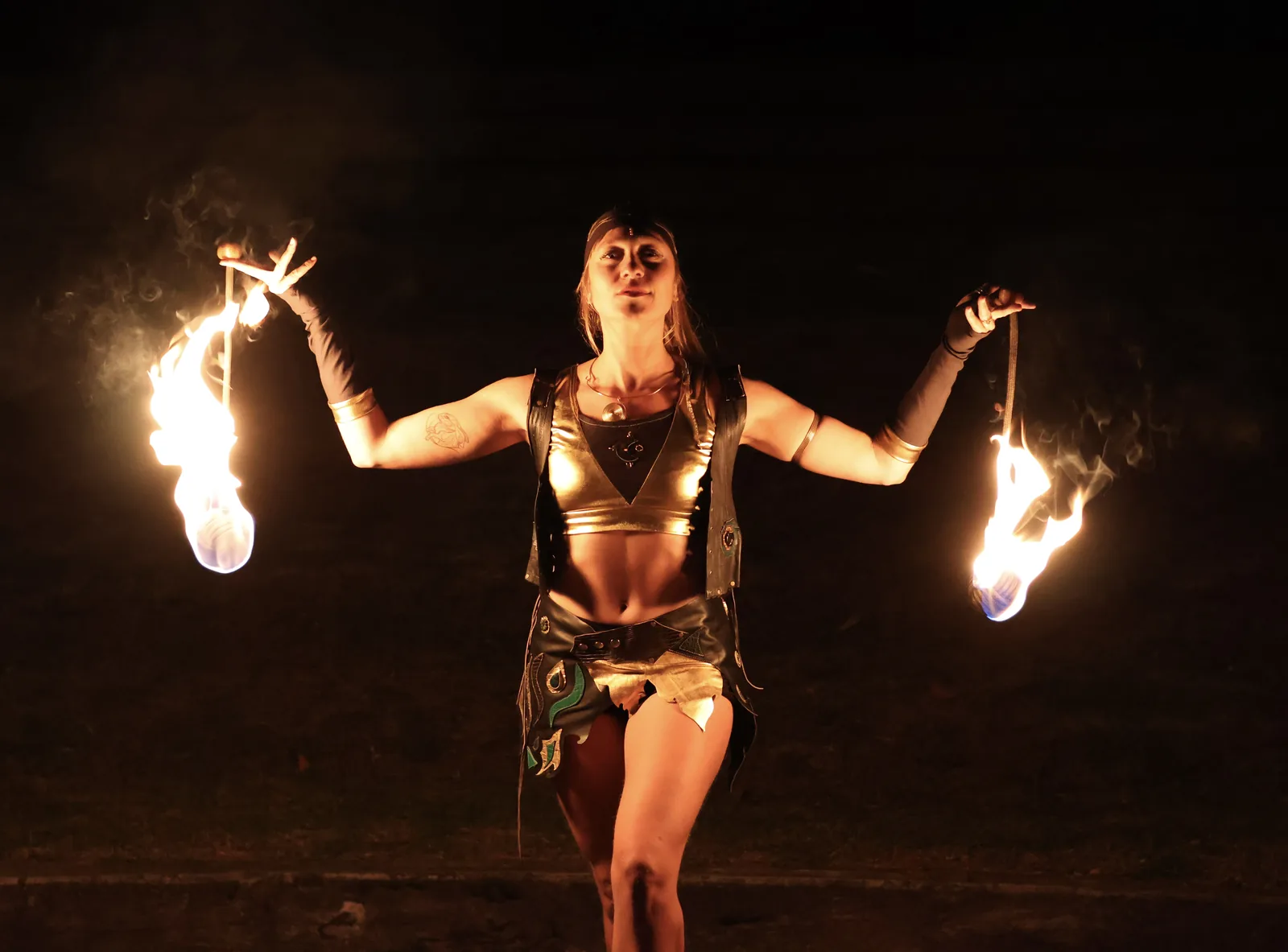 Performer walking with two burning dragon staffs