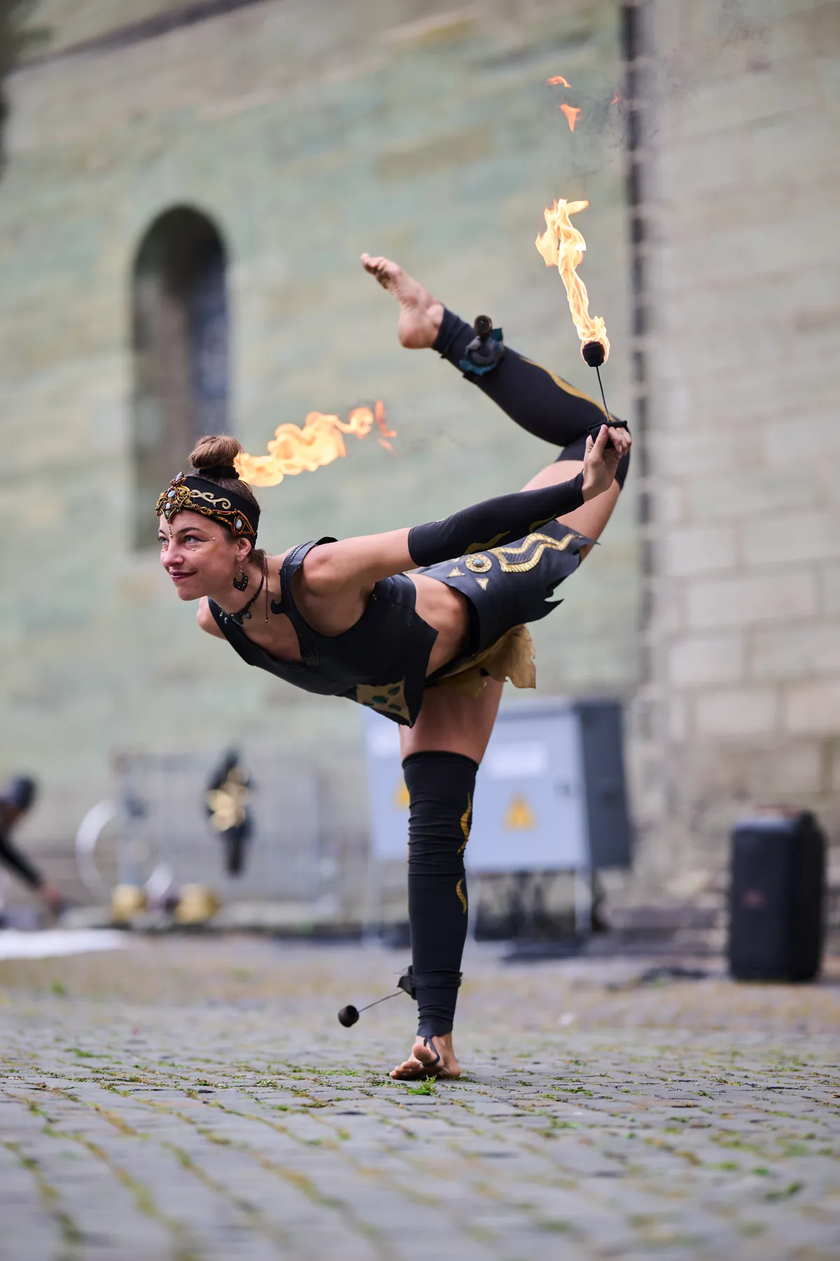 Mascha mid-kick with burning staffs