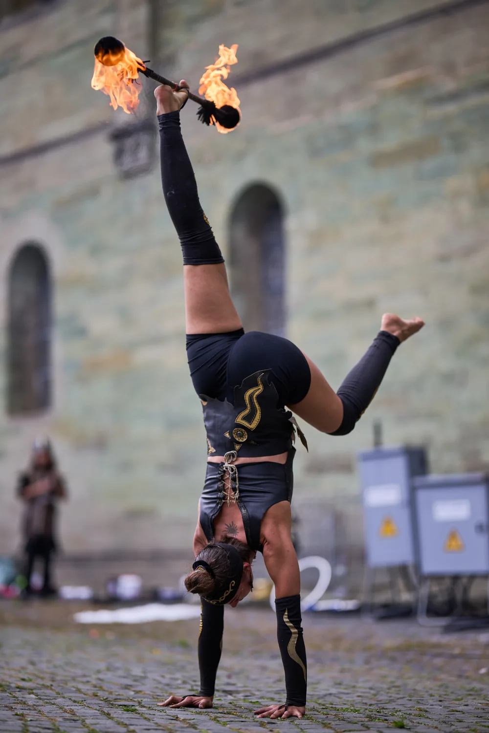 Mascha in a handstand holding burning staffs