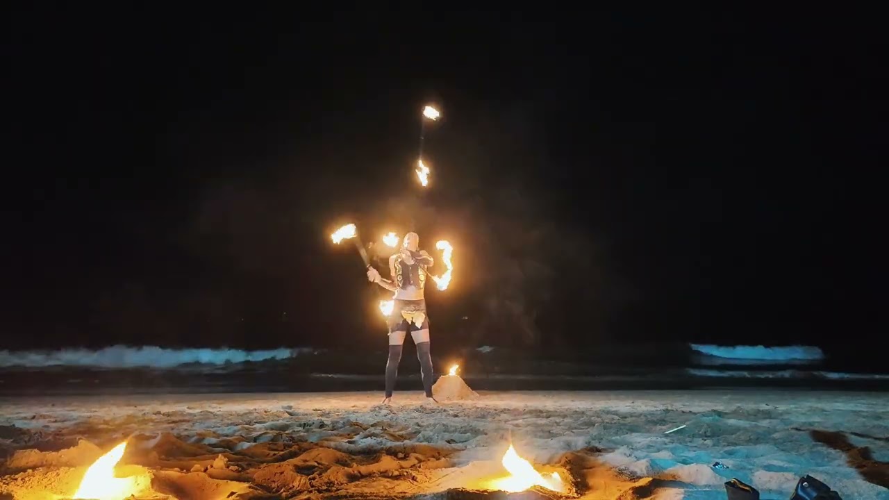 Juggling staff fire act on the beach